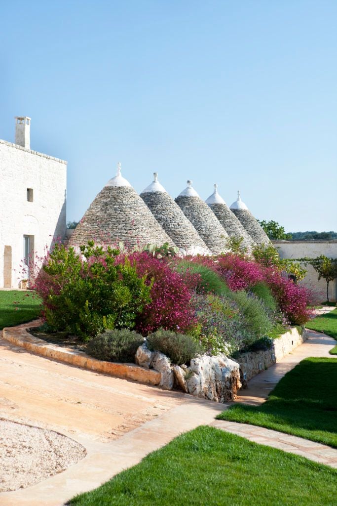 Rustic stone farmhouse nestled in Puglia's countryside, with sun-drenched stone walls, traditional architecture, and lush Mediterranean landscape