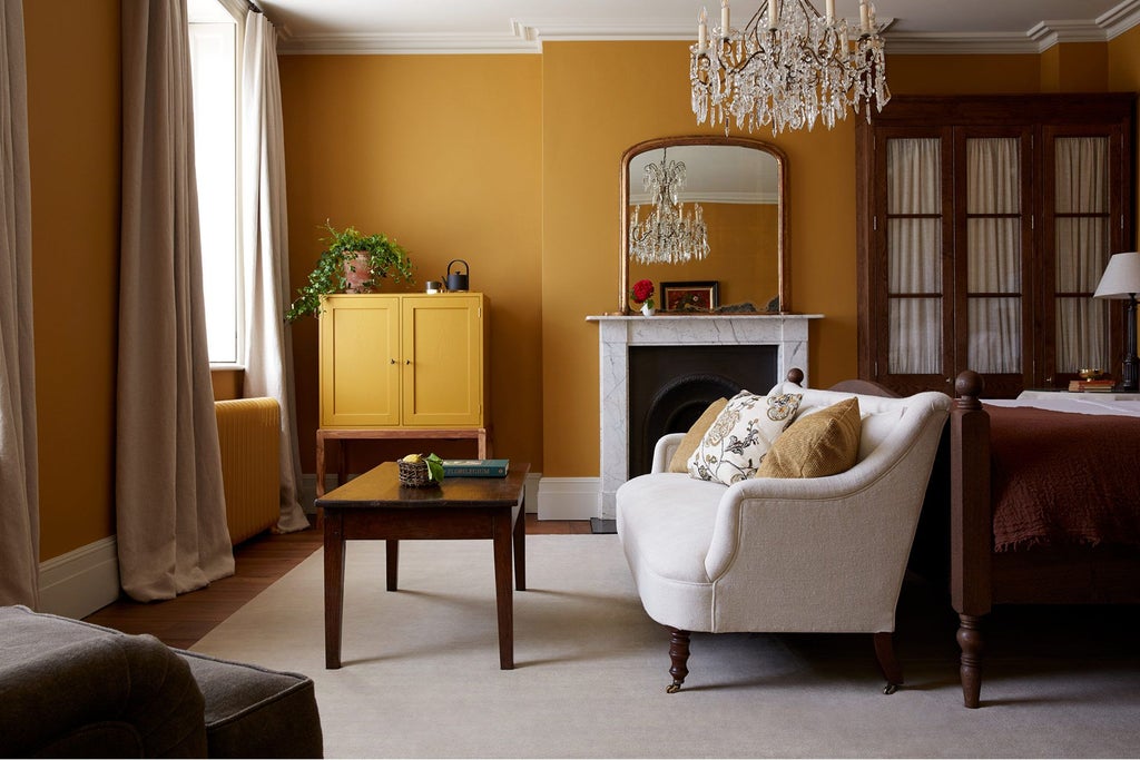 Luxurious ochre-toned hotel room at Heckfield Place, featuring elegant furnishings, soft natural light, and refined minimalist design in a tranquil UK countryside setting