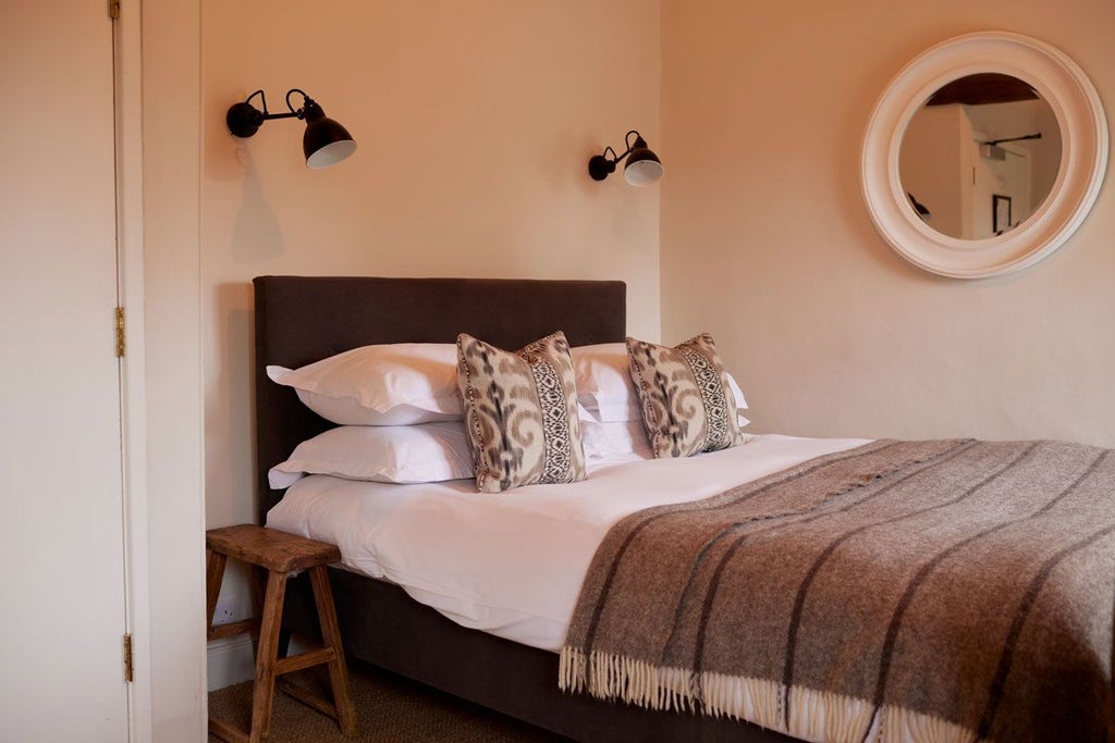 Elegant boutique hotel room with soft neutral tones, plush bedding, modern minimalist design, and warm ambient lighting in a historic United Kingdom setting