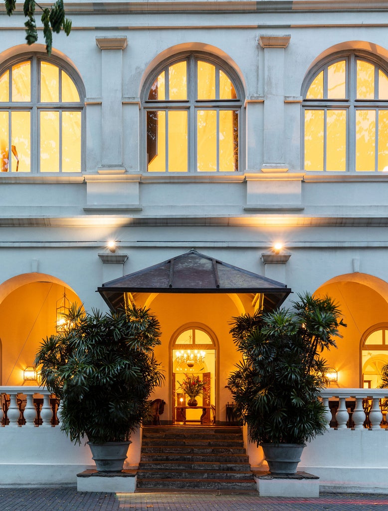 Colonial-era luxury hotel with grand white facade, towering palm trees, and manicured garden courtyard in historic Galle Fort, Sri Lanka