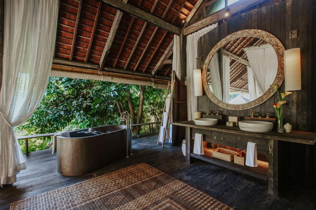 Open-air luxury villa in Bali with infinity pool overlooking lush jungle valley, featuring thatched roof and natural wood design