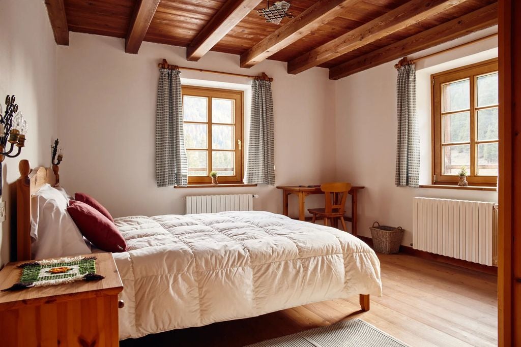 Historic alpine lodge hotel nestled in Dolomites mountains, featuring rustic wood facade, flower-filled balconies and snow-capped peaks backdrop