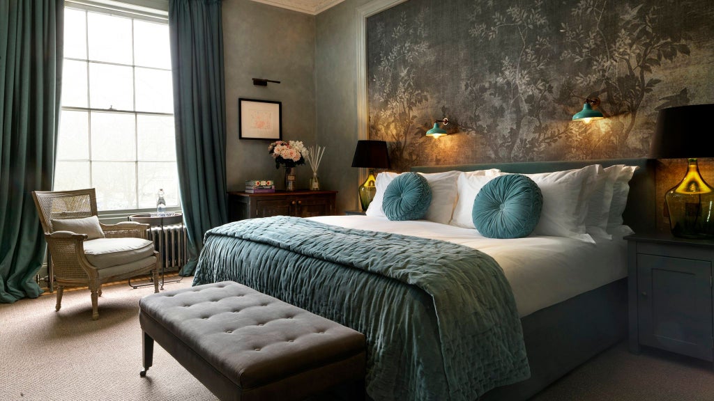 Luxurious hotel room with elegant neutral decor, plush white bedding, modern minimalist furniture, and warm ambient lighting in a UK boutique hotel