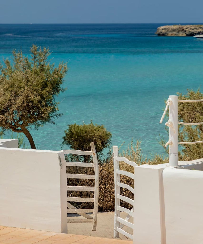 Modern Mediterranean luxury hotel with sleek white exterior, ocean-view balconies, and an infinity pool overlooking turquoise waters