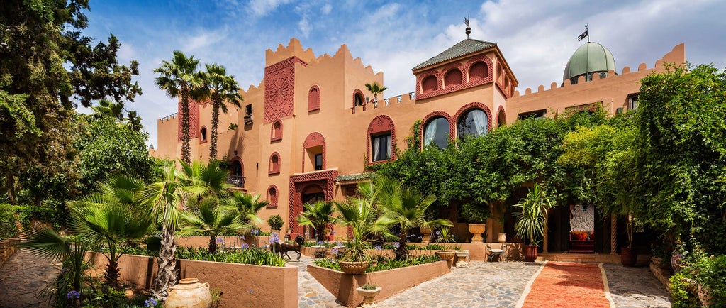 Luxurious Moroccan resort with red clay buildings nestled in Atlas Mountains, featuring infinity pool and traditional architecture