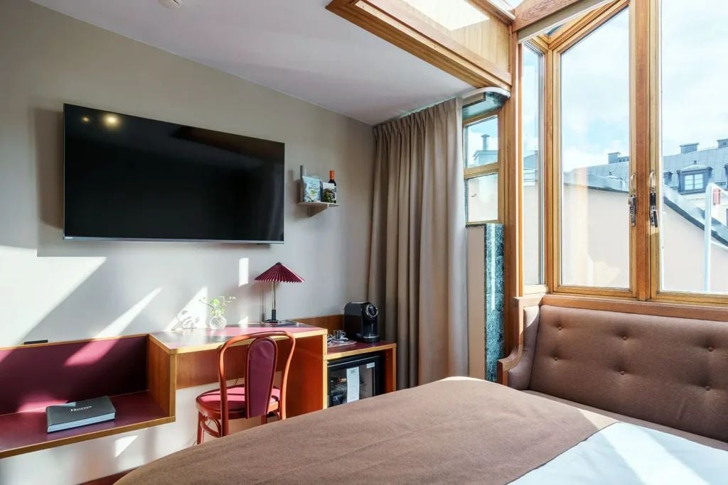 Elegant Swedish hotel room with warm wood tones, plush white bedding, minimalist decor, and soft ambient lighting creating a cozy, luxurious atmosphere