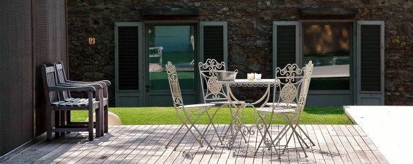 Minimalist luxury loft with stone walls, wooden floors, and modern designer furniture overlooking a serene Tuscan landscape near Florence