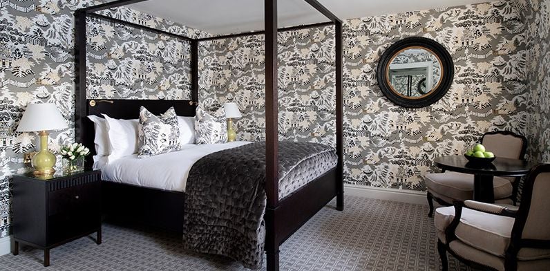 Elegant studio suite with plush king bed, modern grey headboard, sleek city view window, and luxurious marble-tiled bathroom in a prestigious United Kingdom hotel.