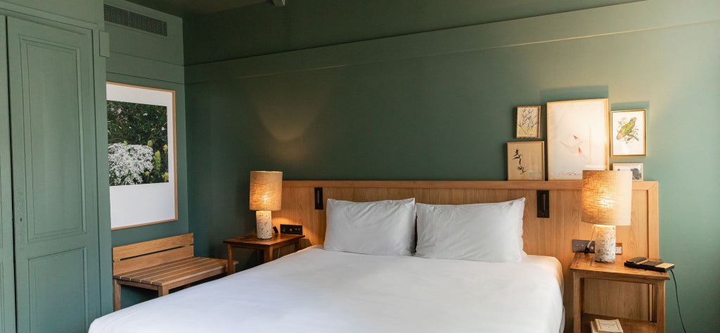 Elegant French luxury hotel room with soft neutral tones, plush bedding, refined wooden furniture, and soft natural lighting at Les Sources de Cheverny