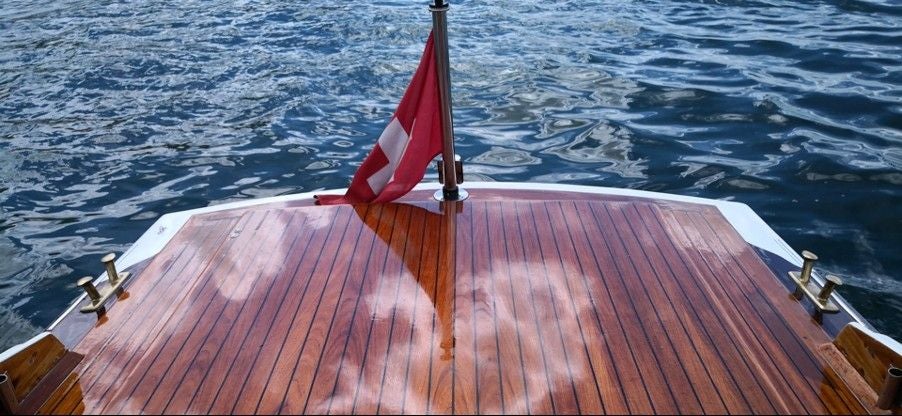 Elegant boat gliding through Zurich's crystal-clear waters, framed by historic Swiss architecture and snow-capped Alpine mountains in golden afternoon light