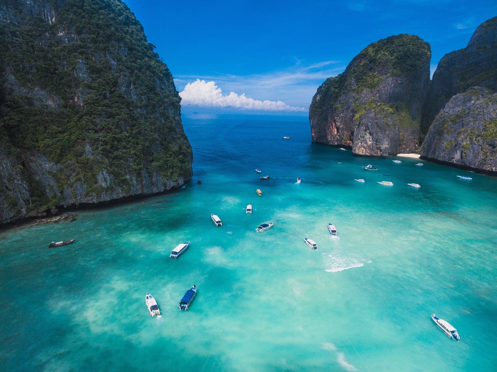 Sleek white speedboat cutting through turquoise waters, surrounded by dramatic limestone cliffs of Phi Phi Islands, with tourists enjoying sunny tropical adventure