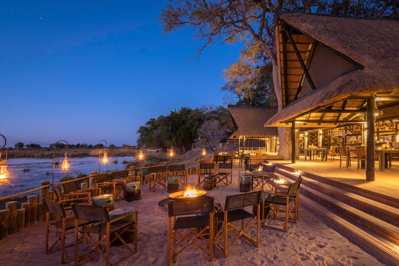 Luxurious safari lodge with thatched-roof villa overlooking a tranquil river, private deck with plunge pool and panoramic savanna views