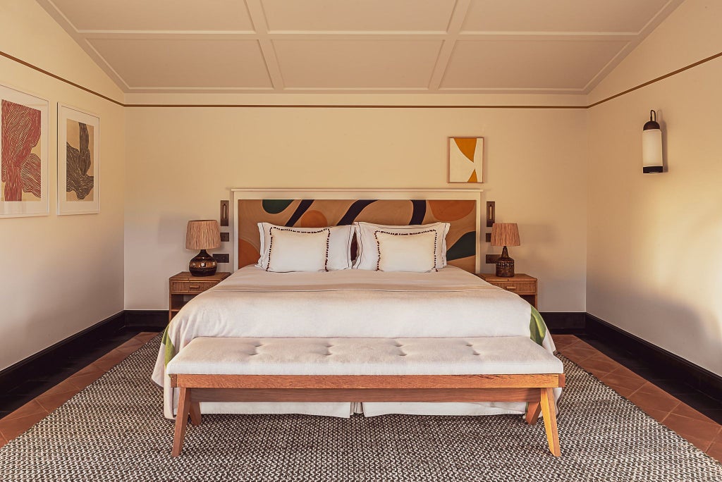 Luxurious prestige suite at Lou Pinet hotel in France, featuring elegant white linens, modern design, and soft natural lighting with subtle blue accents.