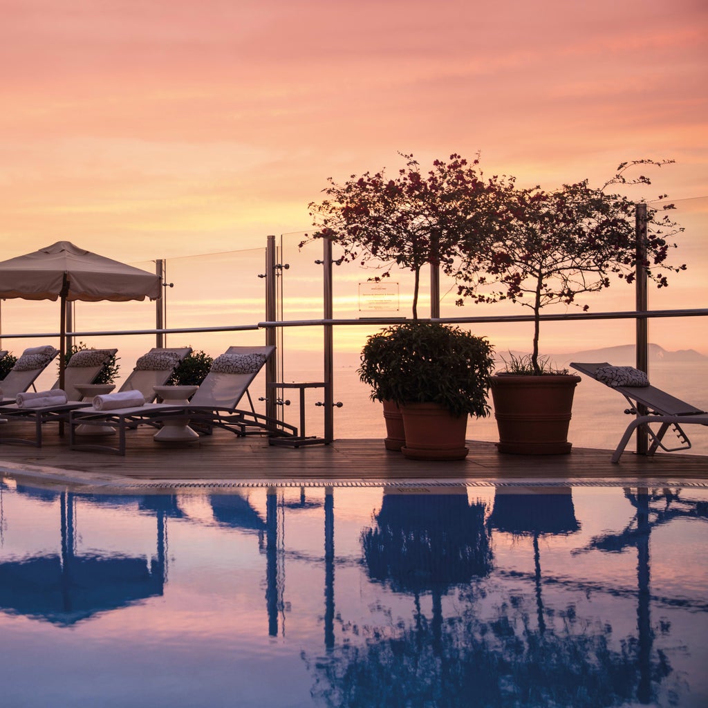 Ocean-view luxury hotel with modern high-rise architecture, featuring a rooftop infinity pool and palm-lined terrace overlooking Lima's coastline