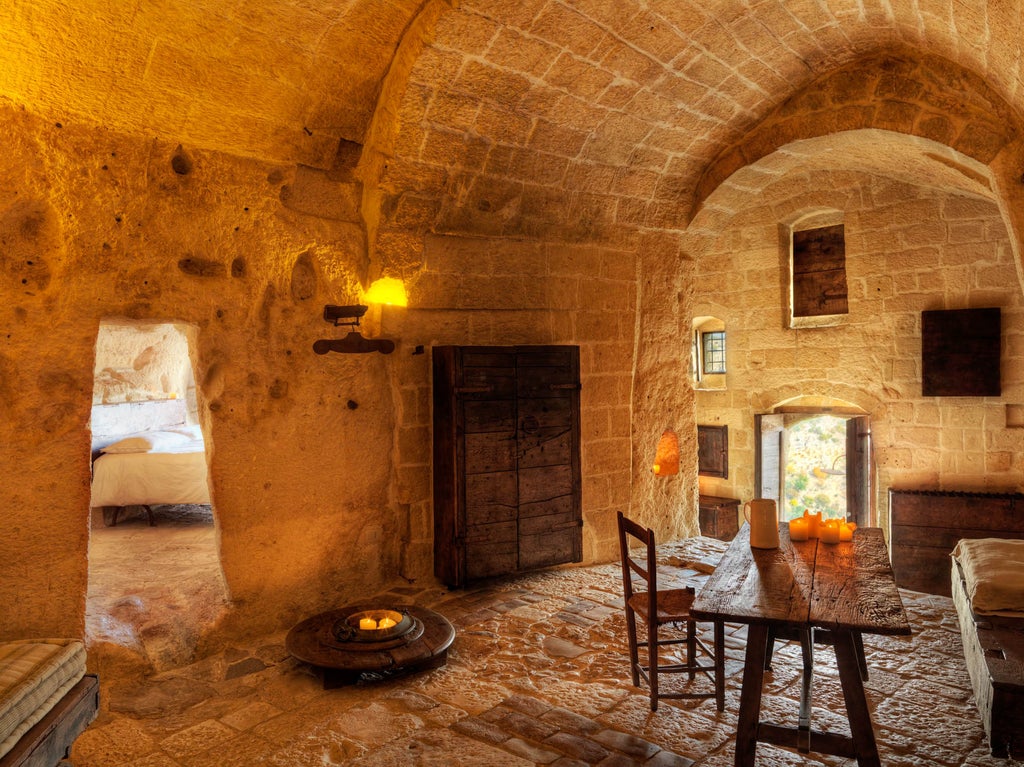 Historic Italian cave hotel room with stone walls, arched ceiling, elegant freestanding bathtub, and romantic candlelit ambiance