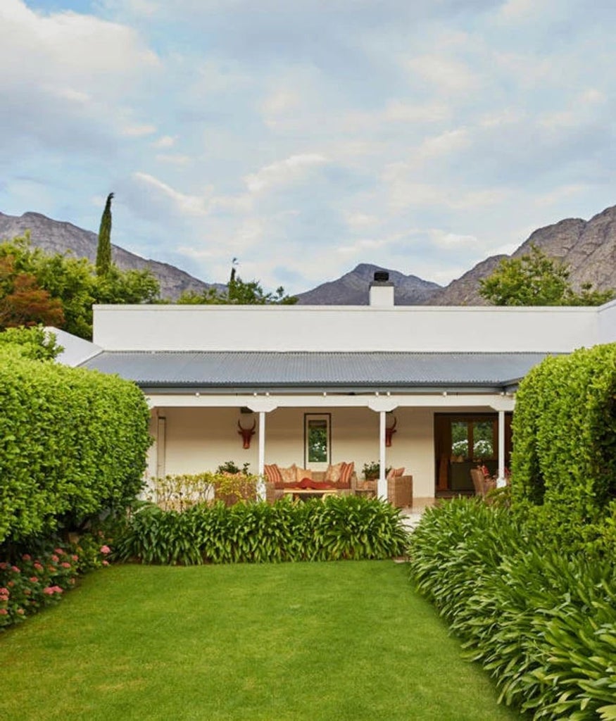 Elegant boutique hotel nestled in Cape Winelands, featuring French colonial architecture, lush gardens, and mountain backdrop