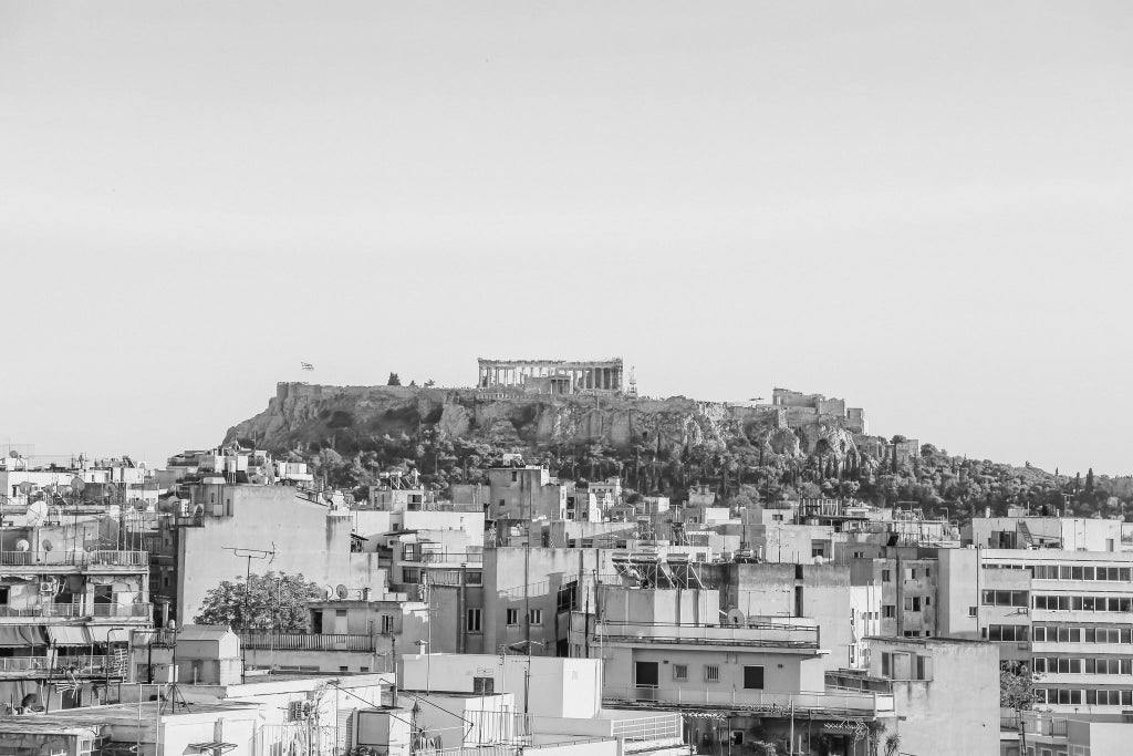 Elegant rooftop terrace of boutique hotel in Athens, Greece, with minimalist design, overlooking historic cityscape and ancient architecture at sunset