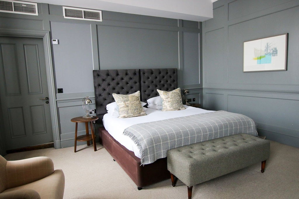 Spacious luxury feature room with elegant king-sized bed, rich wood furnishings, plush textiles, and warm ambient lighting at Kings Head Hotel, UK.