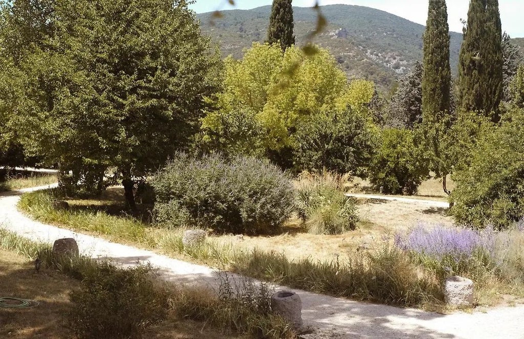 Elegant stone boutique hotel with terracotta-tiled roof nestled in lavender-lined Provence landscape, warm sunlight illuminating rustic French architectural charm