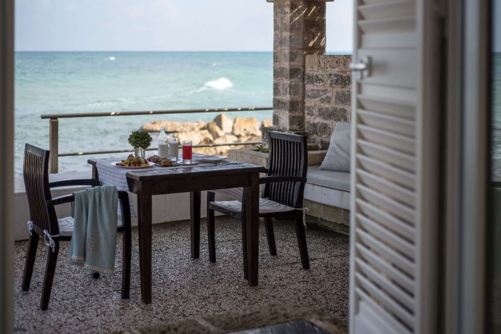 Luxurious panoramic suite with expansive terrace overlooking azure waters, blending modern Italian design and stunning coastal scenery at La Peschiera Hotel