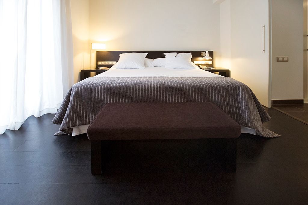 Luxurious white-themed hotel room with modern minimalist design, elegant wooden floor, and plush white bedding at Hospes Palau de la Mar in Valencia