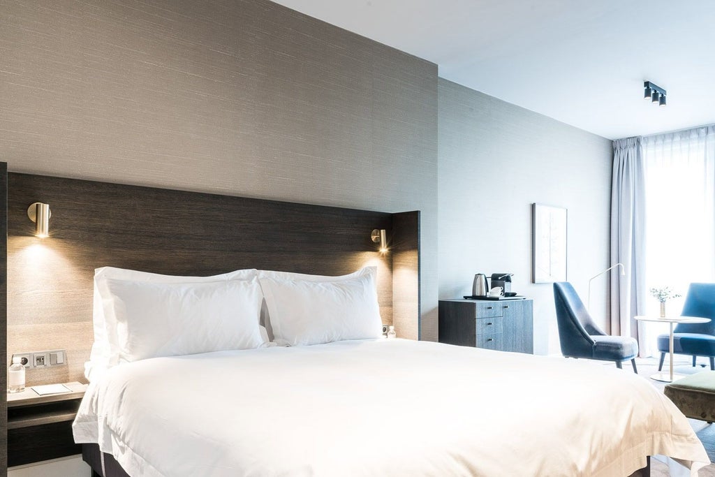 Elegant hotel suite with plush white bedding, modern minimalist design, soft neutral tones, and sophisticated Belgian interior styling in Reylof's luxurious accommodation