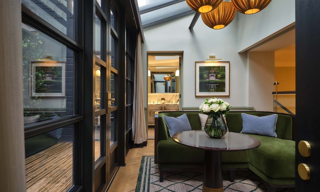 Elegant garden suite with plush emerald green velvet sofa, marble coffee table, and botanical-inspired artwork in luxurious London hotel room