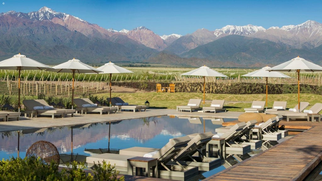 Modern luxury resort nestled in Argentinian wine country with stone and wood facade, panoramic Andes mountain views and infinity pool