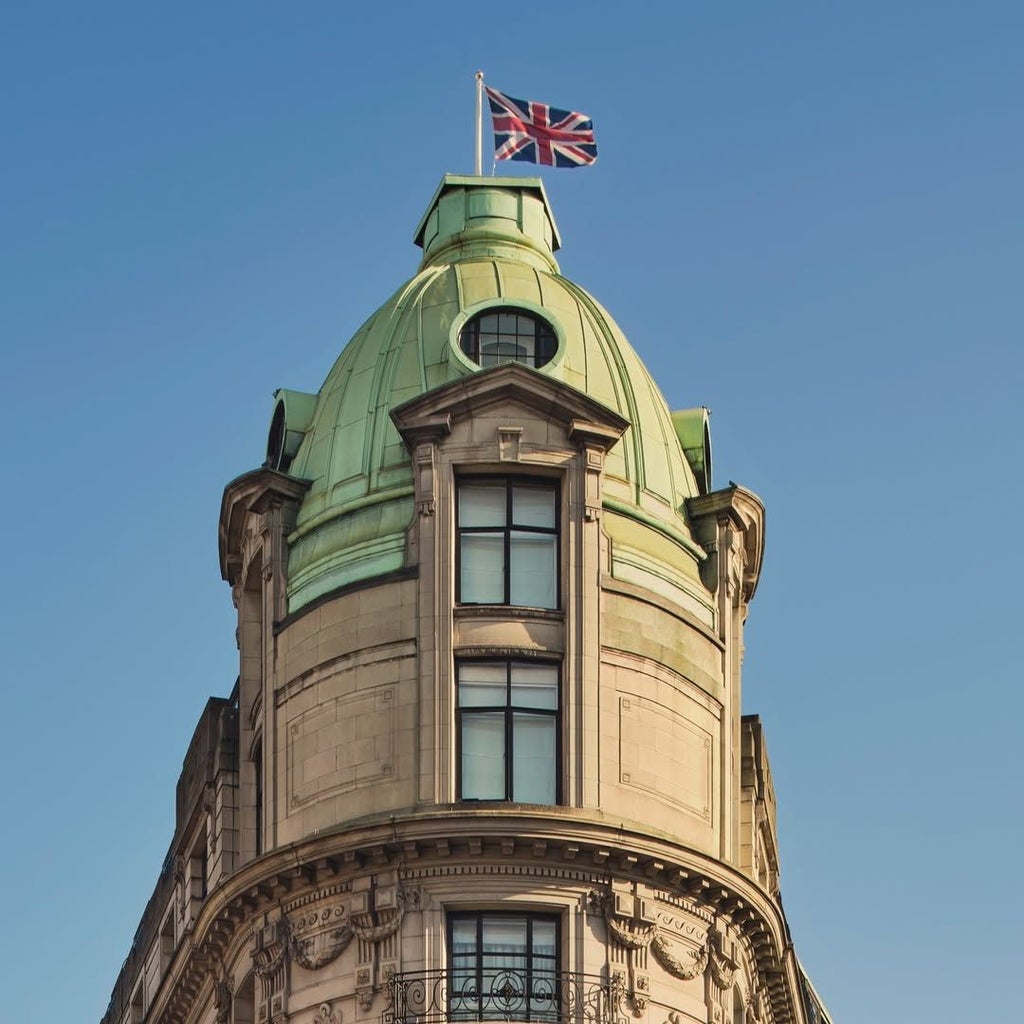 Elegant art deco facade of One Aldwych hotel in London, featuring gleaming white exterior, ornate architectural details, and grand entrance with polished windows