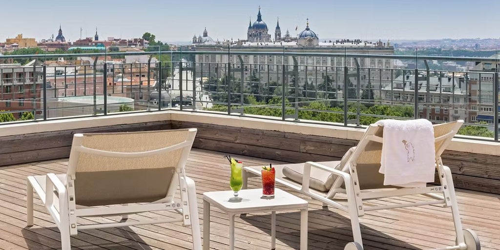 Luxurious landmark hotel with sleek modern architecture rising against Madrid's skyline, showcasing contemporary design and elegant urban sophistication