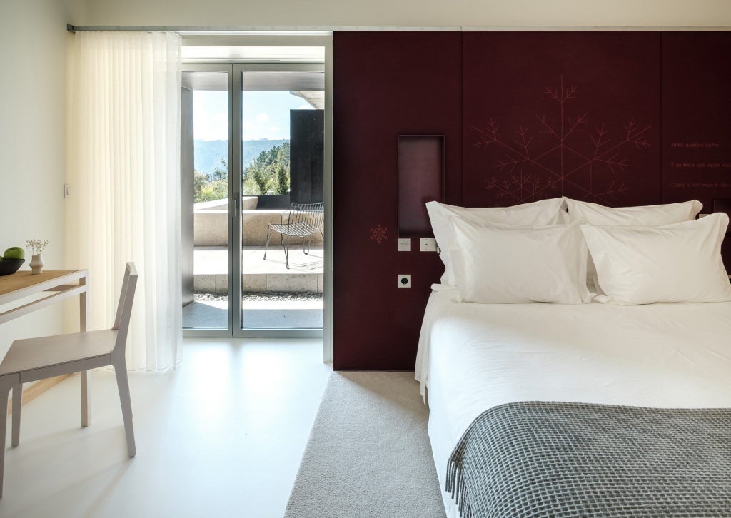 Luxurious mountain-view hotel room with minimalist design, warm wooden accents, and panoramic windows overlooking scenic Portuguese landscape at scenset resort