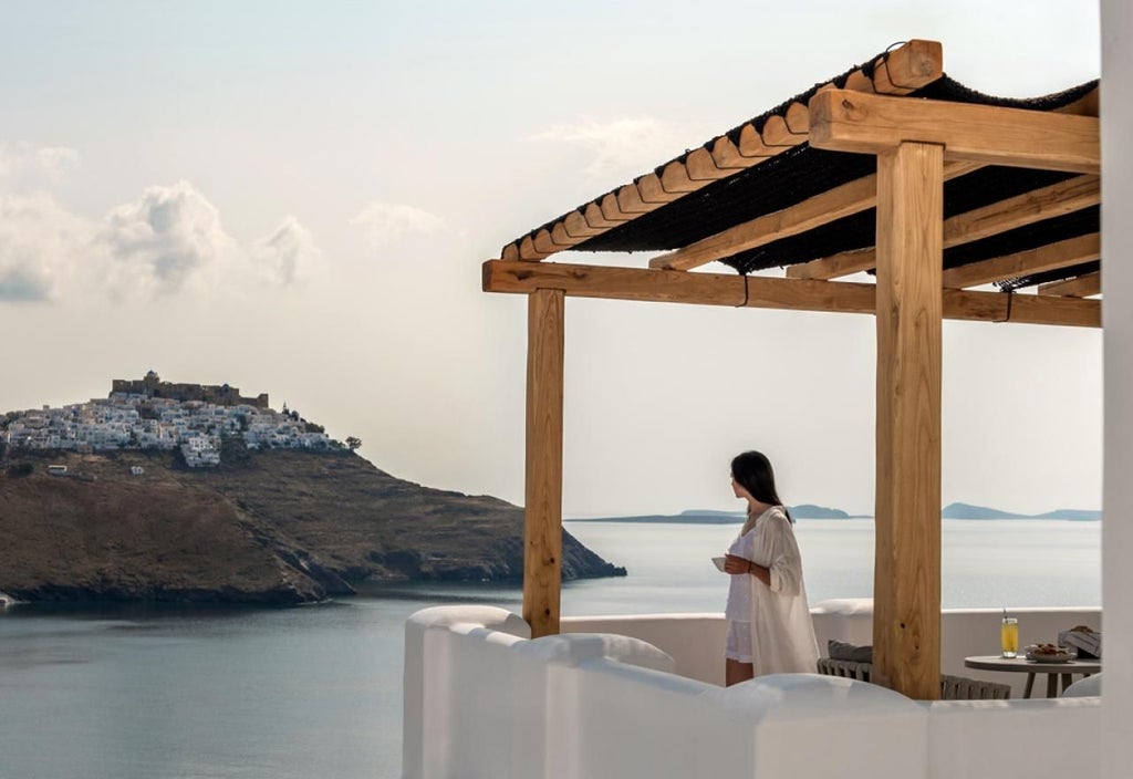 Elegant Grecian honeymoon suite with white minimalist decor, luxurious king bed, and panoramic blue sea view from private balcony at scenic coastal location