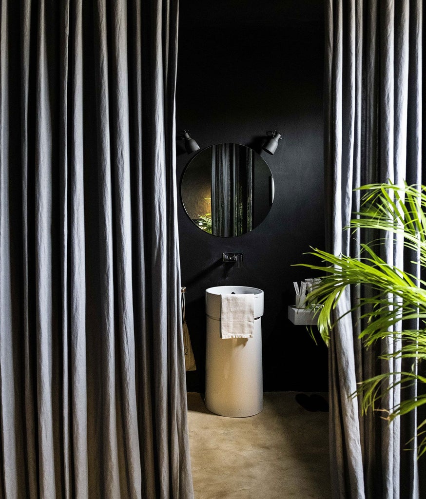 Luxurious black-themed hotel suite with minimalist design, high-end Italian furnishings, and dramatic architectural details in Palazzo Daniele, Puglia