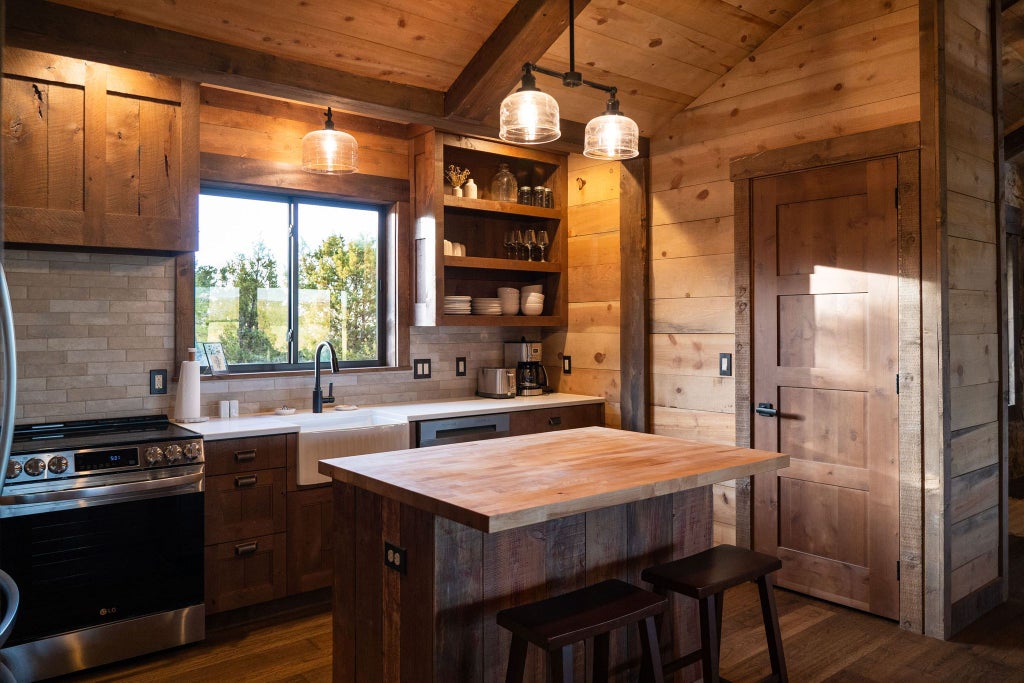 Rustic lodge bedroom with wooden furniture, plush bedding, and large windows overlooking scenic mountain landscape at Scenset Mountain Ranch accommodation