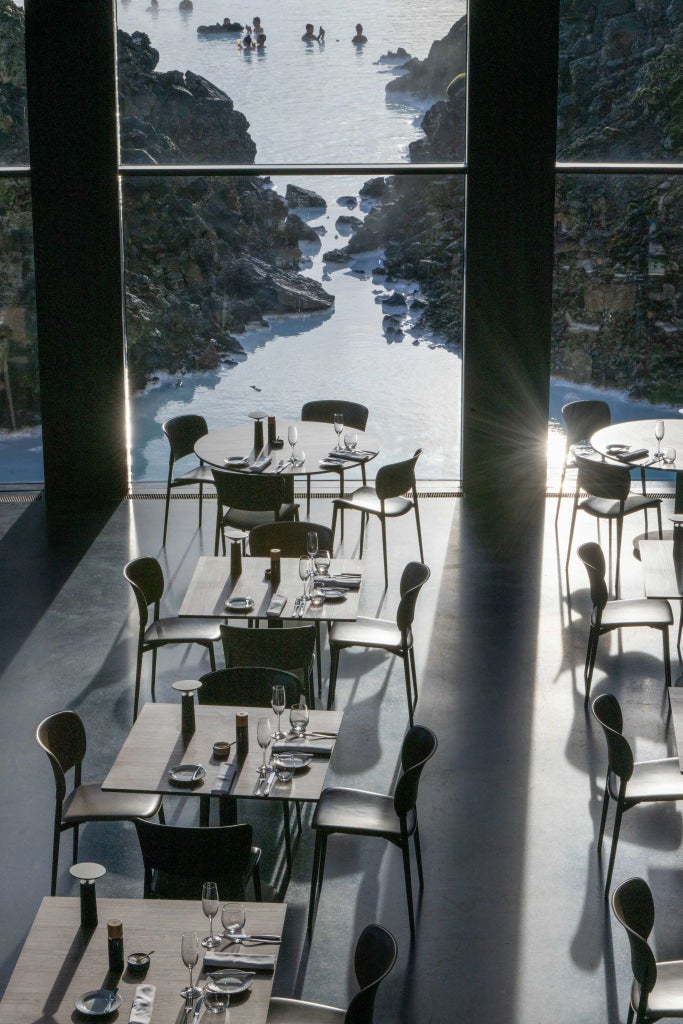 Modern minimalist Icelandic hotel room with panoramic window, sleek Nordic design, volcanic stone accents, and soft neutral color palette overlooking dramatic landscape