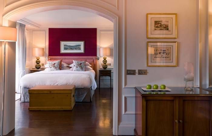 Luxurious wood-paneled hotel suite at Chewton Glen Spa with elegant four-poster bed, plush furnishings, and refined countryside retreat ambiance