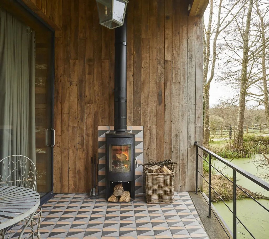 Luxurious rustic lake cabin hotel room with floor-to-ceiling windows, elegant wooden furnishings, and a serene natural landscape view in the United Kingdom.