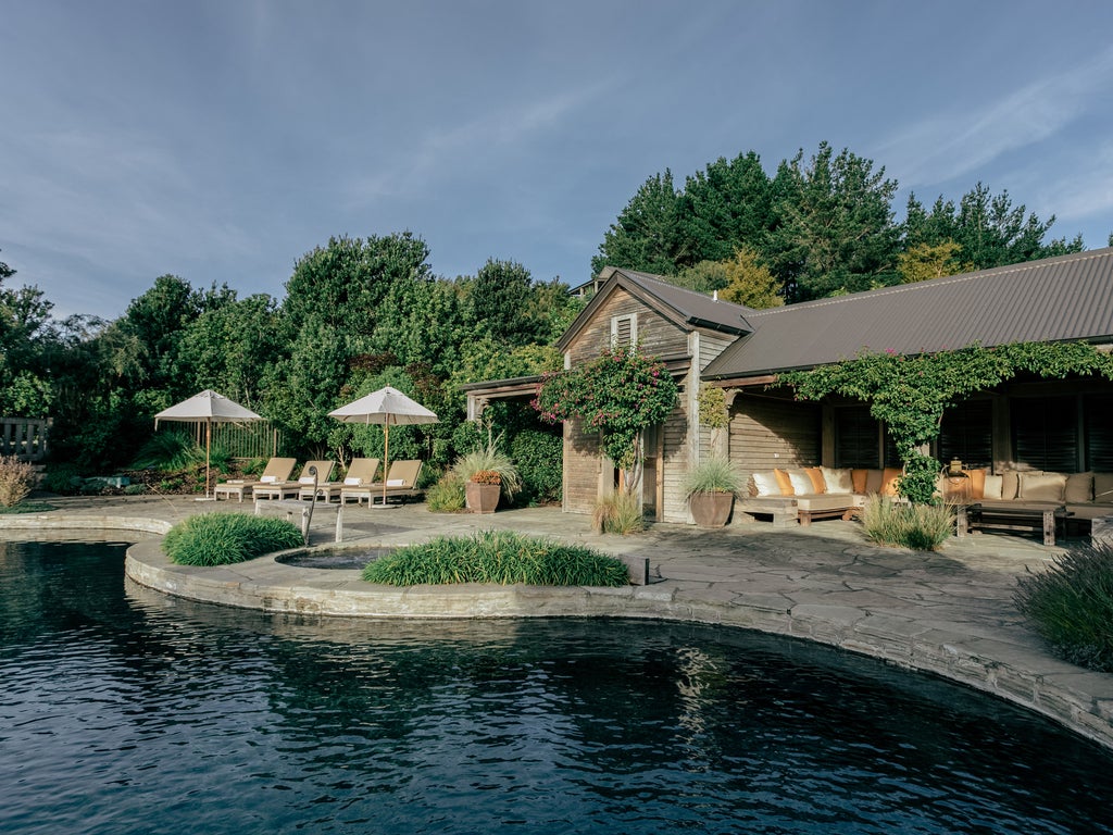 Luxury clifftop lodge with panoramic ocean views, featuring stone walls, timber beams, and manicured gardens overlooking Cape Kidnappers