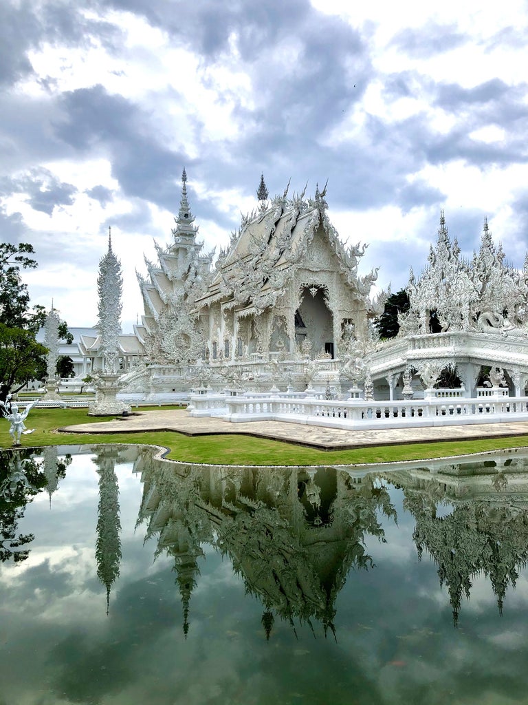 Traditional Thai spa pavilion with ornate golden roof overlooking tranquil gardens in Chiang Rai's lush, mountainous landscape