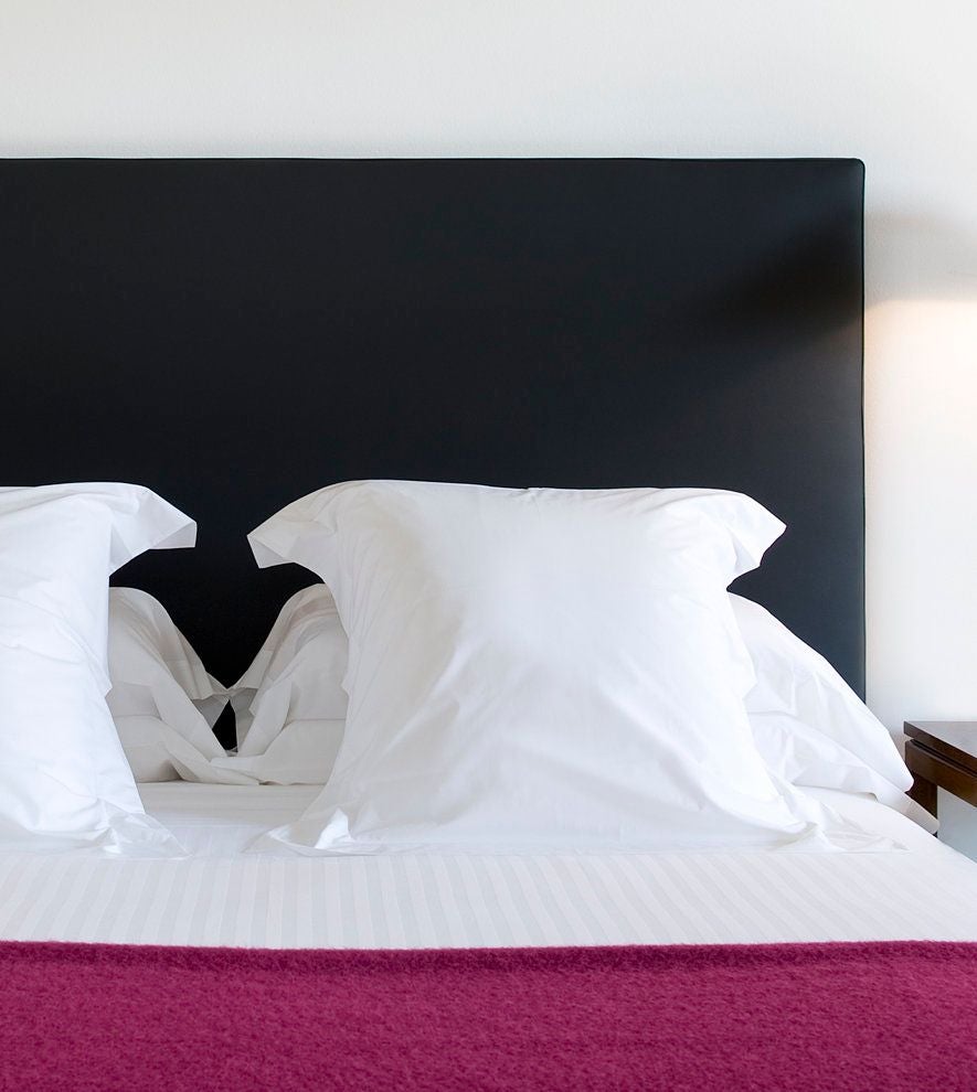 Elegant small hotel room with white linens, minimalist design, wooden floor, soft lighting, and contemporary Spanish decor in neutral tones