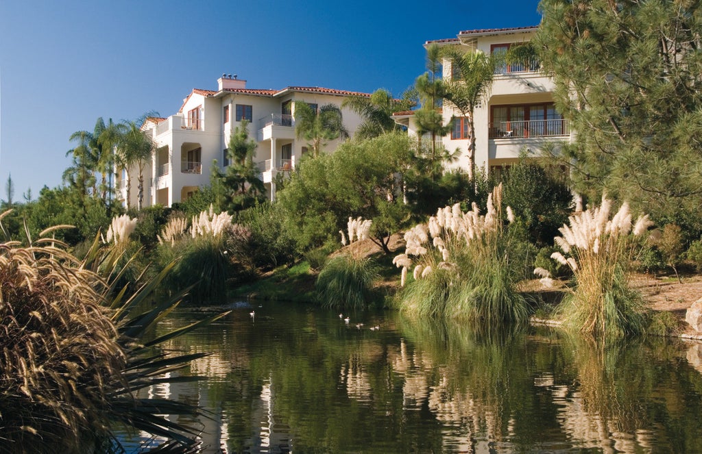 Elegant coastal resort featuring Spanish colonial architecture, palm-lined entrance, and a grand fountain surrounded by manicured gardens