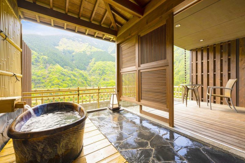 Traditional Japanese onsen hotel perched on mountainside with private hot spring baths overlooking lush Iya Valley forest vista