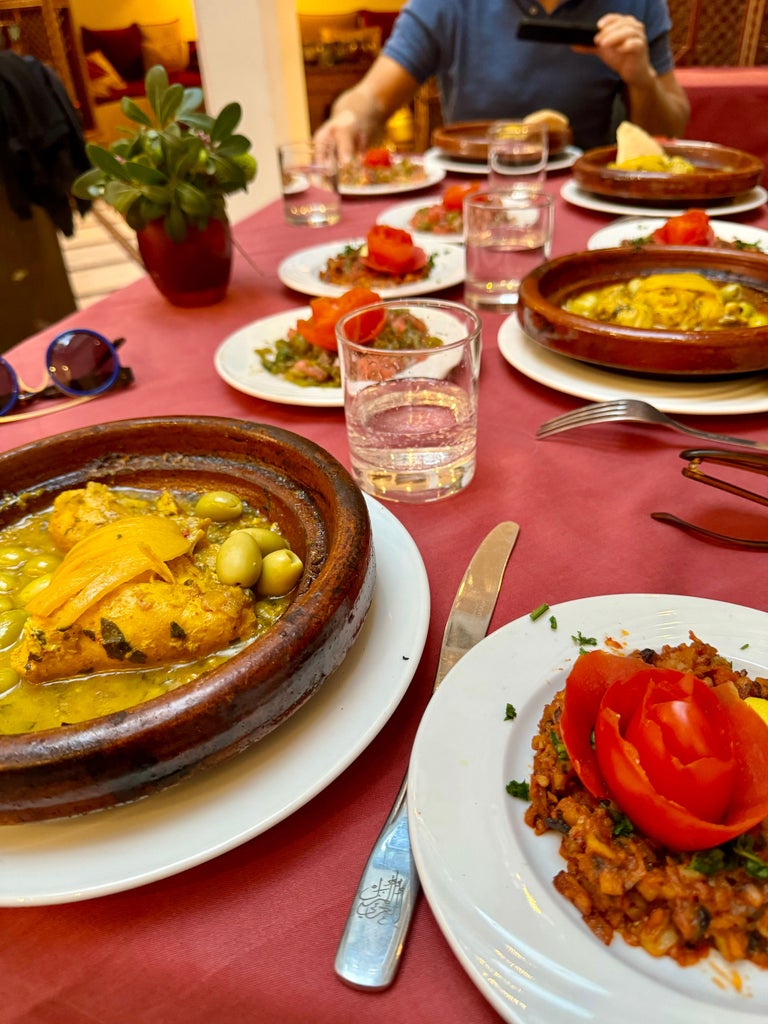 Vibrant cooking class in a luxurious Moroccan kitchen, participants wearing crisp white aprons, surrounded by colorful spices and traditional cookware