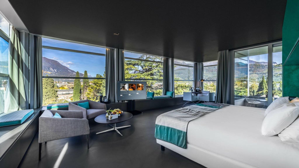 Luxurious sky-high mountain suite in Lido Palace, featuring panoramic Alpine views, elegant contemporary decor, and expansive floor-to-ceiling windows overlooking scenic Italian landscape