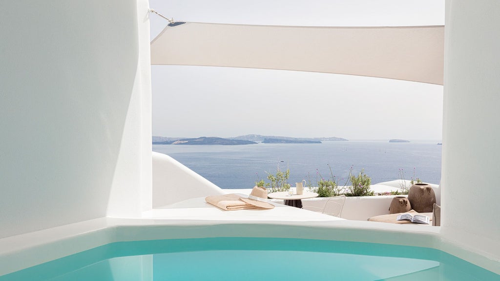 Luxurious white-walled Honeymoon Suite with blue infinity pool overlooking Santorini's caldera, featuring minimalist design and panoramic Aegean Sea views