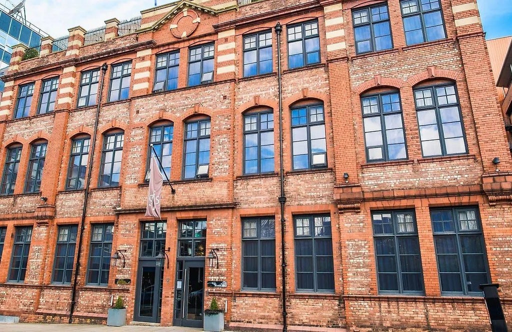 Boutique luxury hotel exterior with historic brick facade, large windows, elegant architectural details overlooking urban streetscape in scenic United Kingdom setting