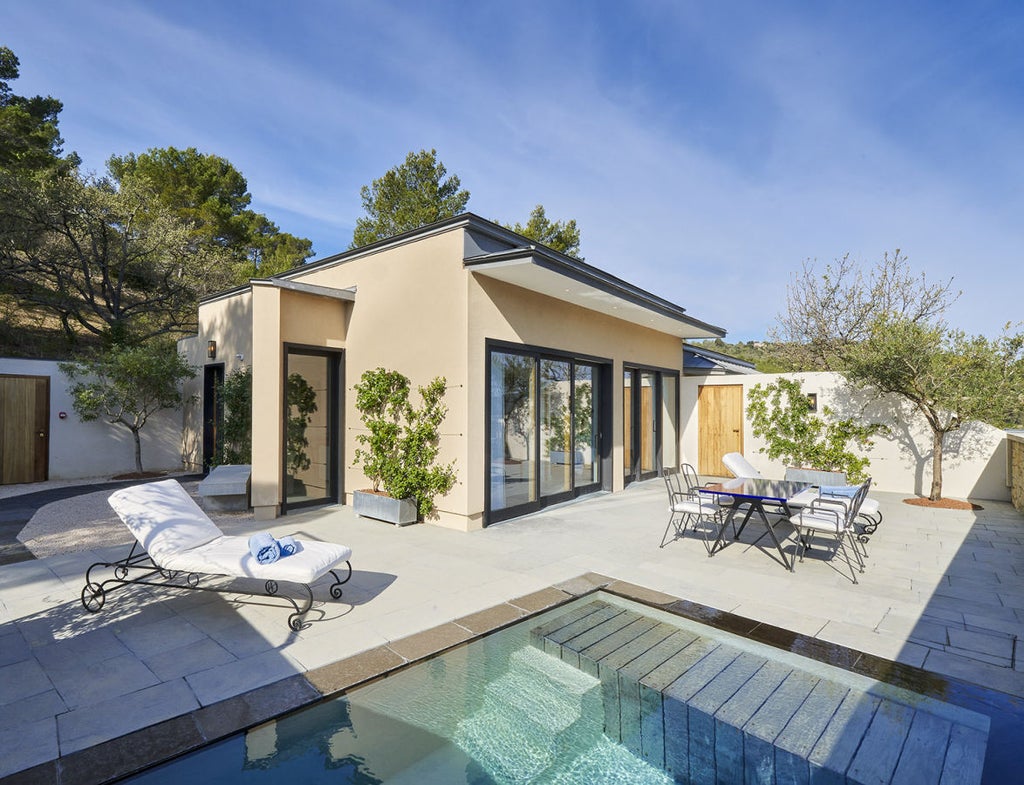 Modern luxury villa suite with private infinity pool overlooking scenic French countryside, featuring sleek glass walls and minimalist design