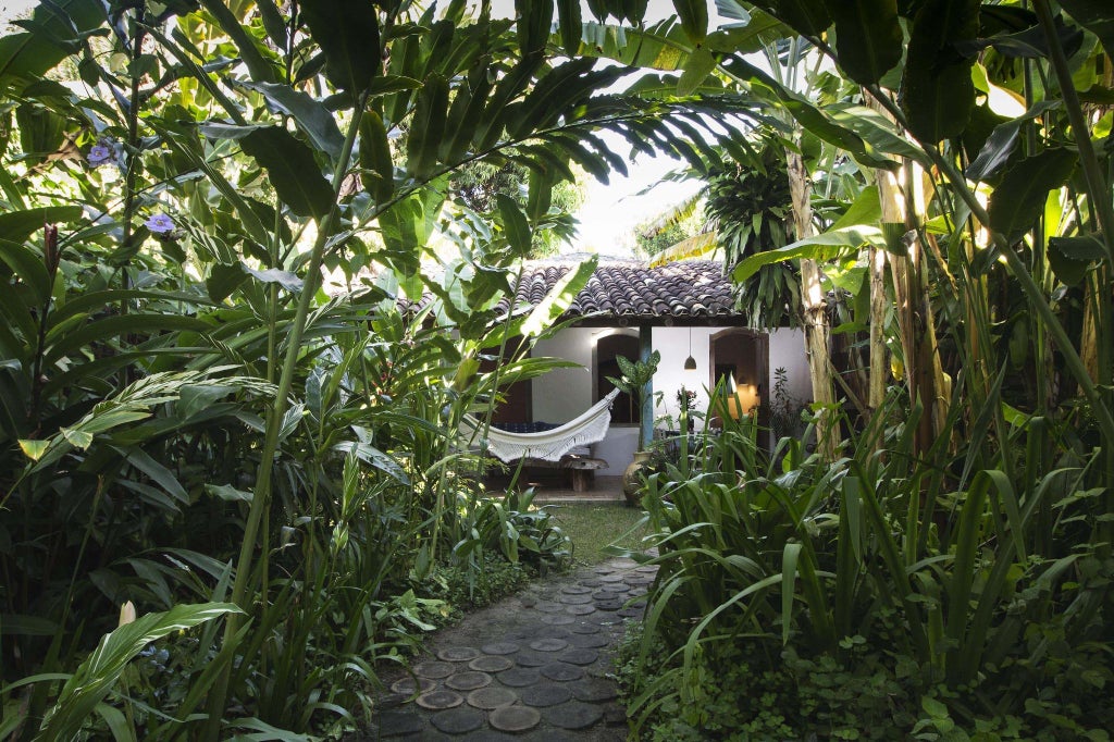 Luxurious tropical villa with rustic wooden architecture, lush green gardens, and a serene pool at UXUA Casa Hotel and Spa in Trancoso, Brazil