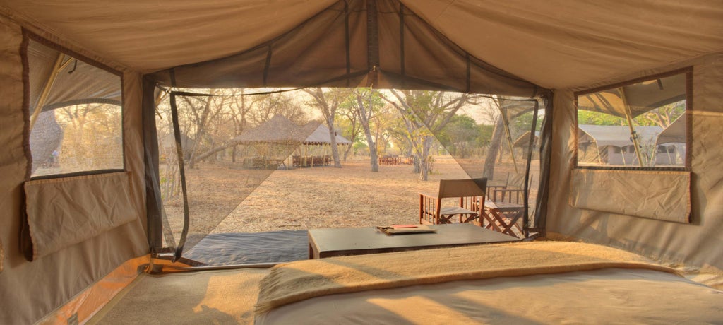 An elegant safari tent overlooking Chobe River, featuring a private furnished verandah and deluxe outdoor seating amid pristine wilderness