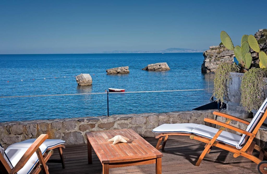 Elegant 5-star Italian coastal hotel with infinity pool overlooking the Mediterranean, set against rocky cliffs at sunset